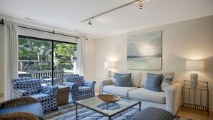 Un salon comprenant un canapé, des fauteuils, une table basse et une grande fenêtre.