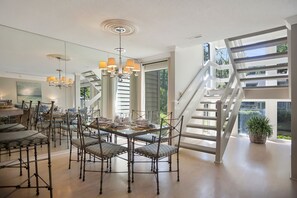 Un comedor amplio con techo alto, una lámpara moderna y una escalera que conduce a un nivel superior.