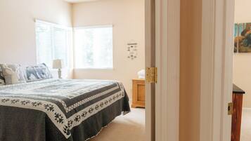 A bedroom with a bed, a nightstand, a window, and a door.