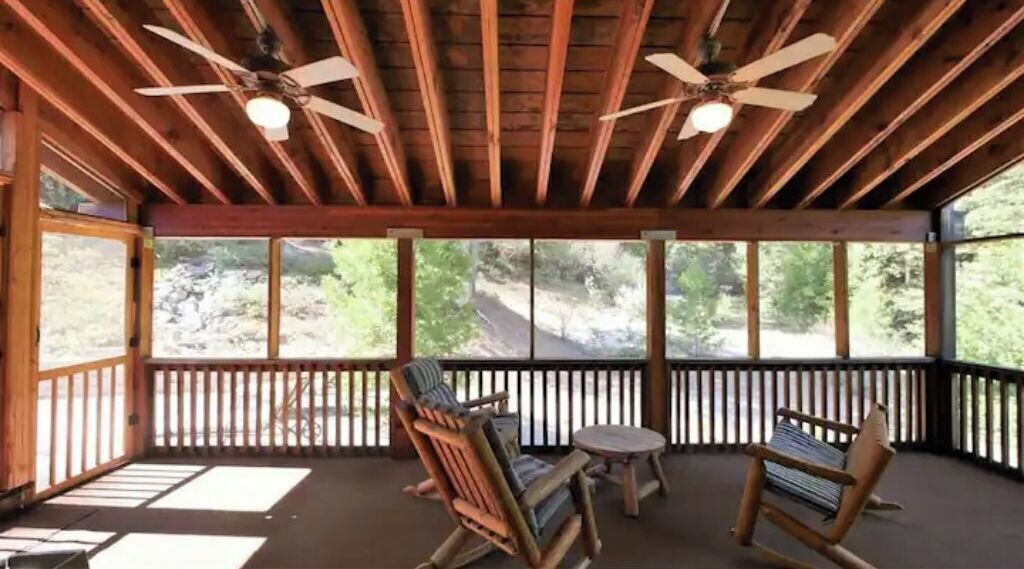 Un espace extérieur abrité, aménagé avec du mobilier en bois et doté de ventilateurs de plafond.