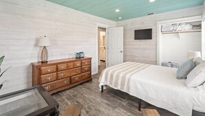 A bedroom with a bed, dresser, and a television mounted on the wall. - SP615  Pet Friendly, In Town, Near Beach (Port Aransas)