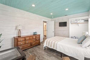A bedroom with a bed, dresser, and a television mounted on the wall. - SP615  Pet Friendly, In Town, Near Beach (Port Aransas)