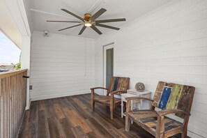 A covered outdoor area with a ceiling fan, two wooden chairs, and a small table.