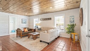 A cozy living room with a wooden ceiling, a beige sofa, a wooden coffee table, and a potted plant. - SP615  Pet Friendly, In Town, Near Beach (Port Aransas)