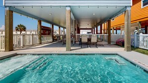 Ein überdachter Poolbereich mit Pool, Sitzgelegenheiten und Blick auf den Ozean.