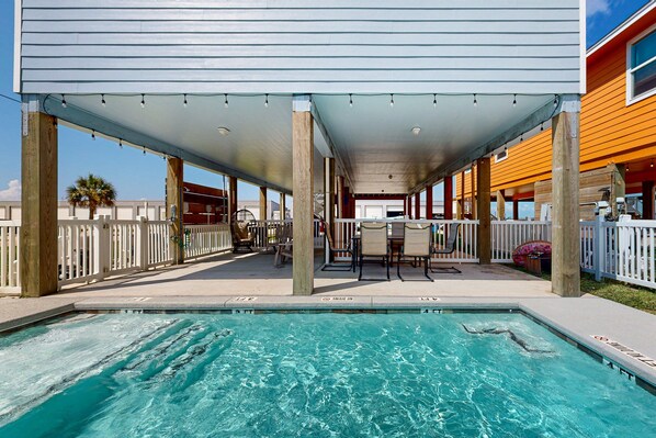 A covered outdoor pool area with a pool, seating, and a view of the ocean. - Private Heated Pool, Parking for 5 (Port Aransas)