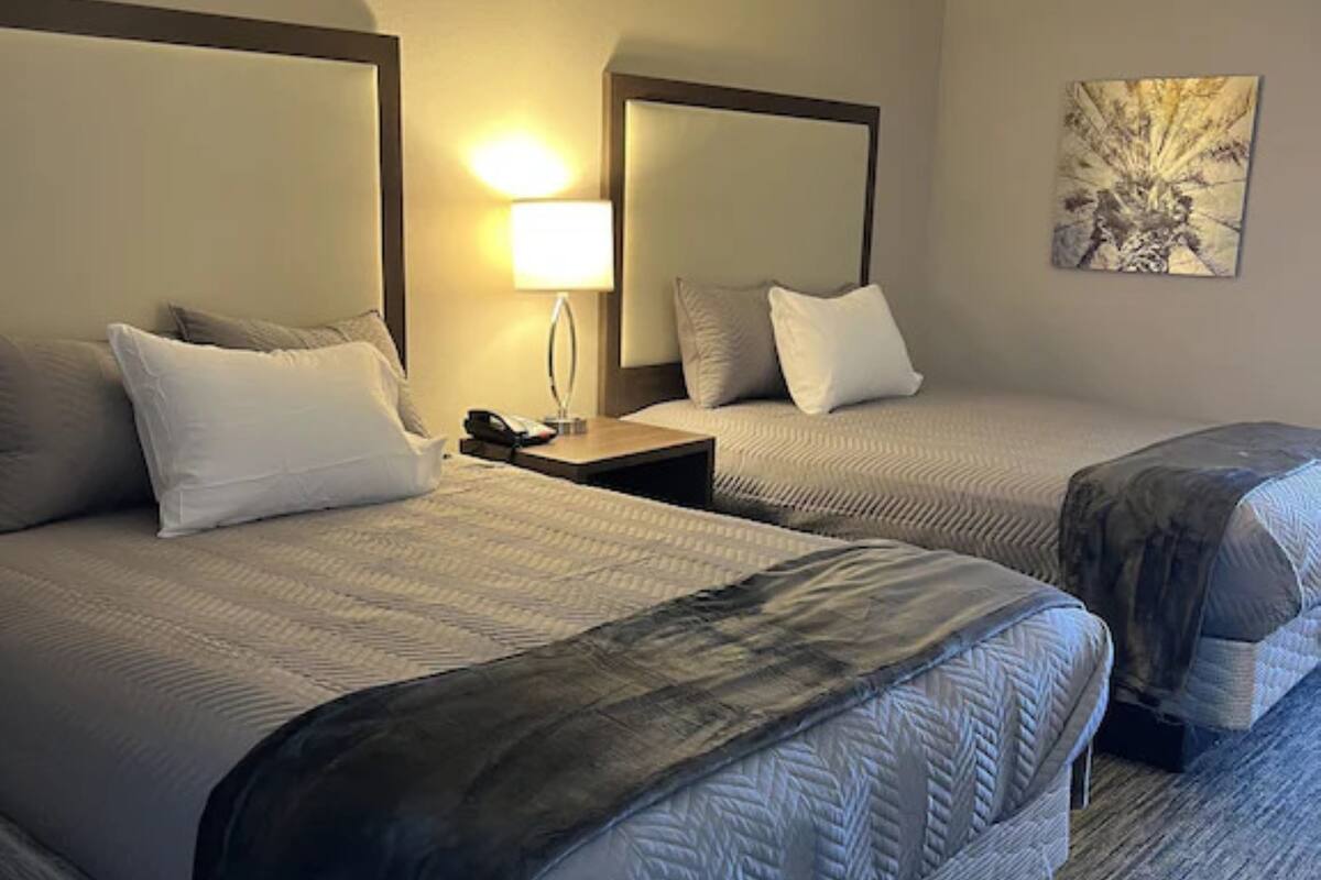 Ein Hotelzimmer mit zwei Betten, einem Nachttisch mit Lampe und einem Bild an der Wand.