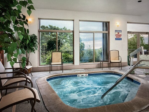 A hot tub area with a view of trees through large windows, a warning sign, and a chair by the window. - Perfect Studio Condo Resort (Galena)