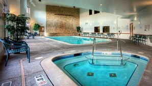 En inomhuspool med en vägg av sten, solstolar och en skylt som förbjuder dykning.
