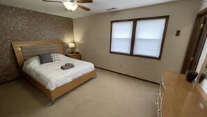Un dormitorio con cama, mesita de noche, lámpara y ventilador de techo.