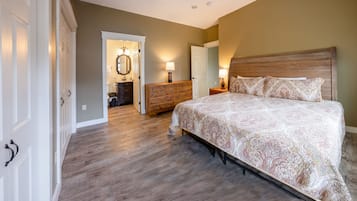 A bedroom with a large bed, wooden dresser, and a bathroom visible through an open door.