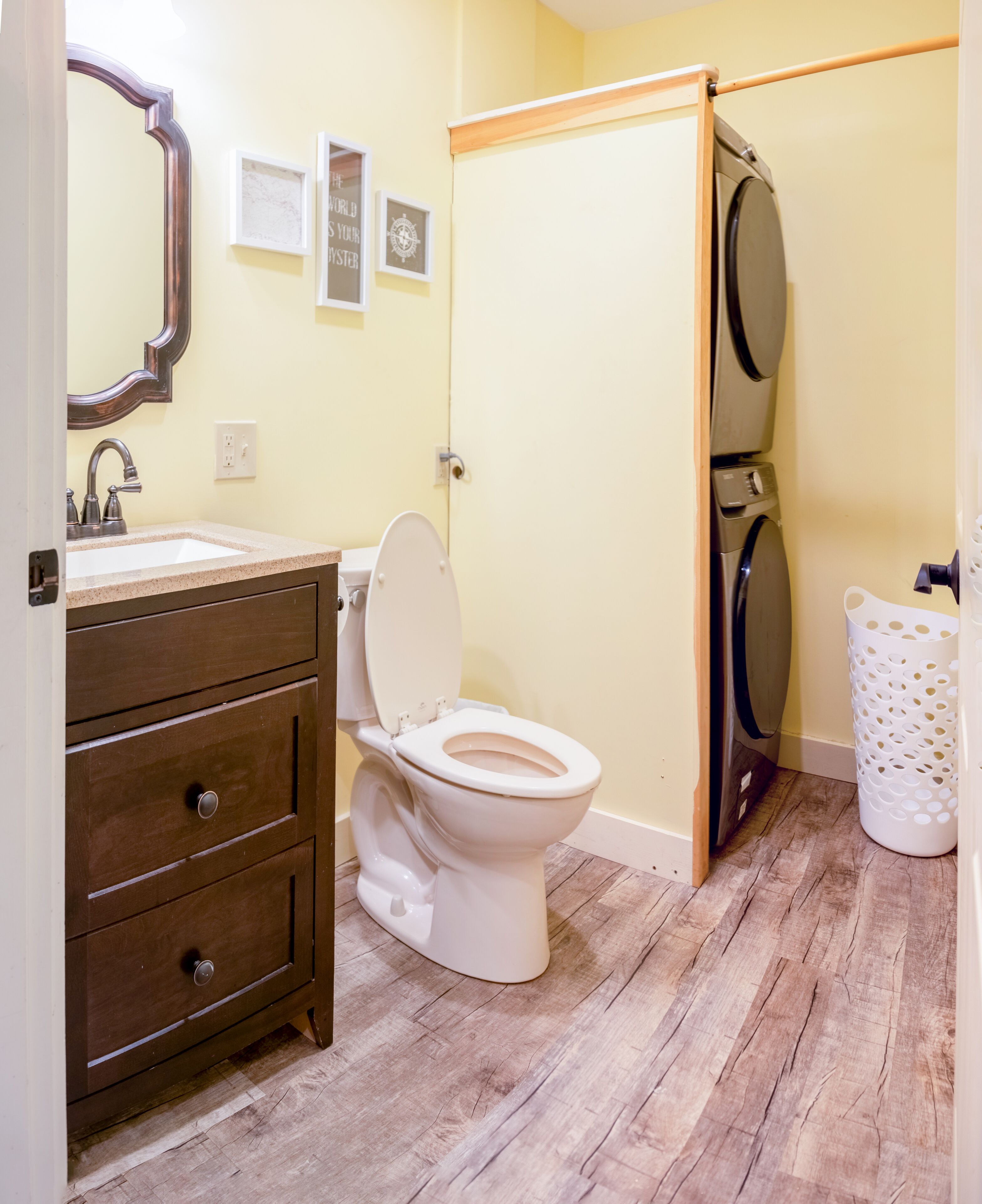 Een badkamer met een houten wastafel, een wit toilet, een spiegel en een wasruimte.
