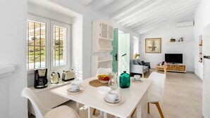 A bright, white room with a dining table set for two, a television, and a sofa. - Stunning private villa for 4 guests with WIFI, private pool, A/C, TV and terrace (Torrox)