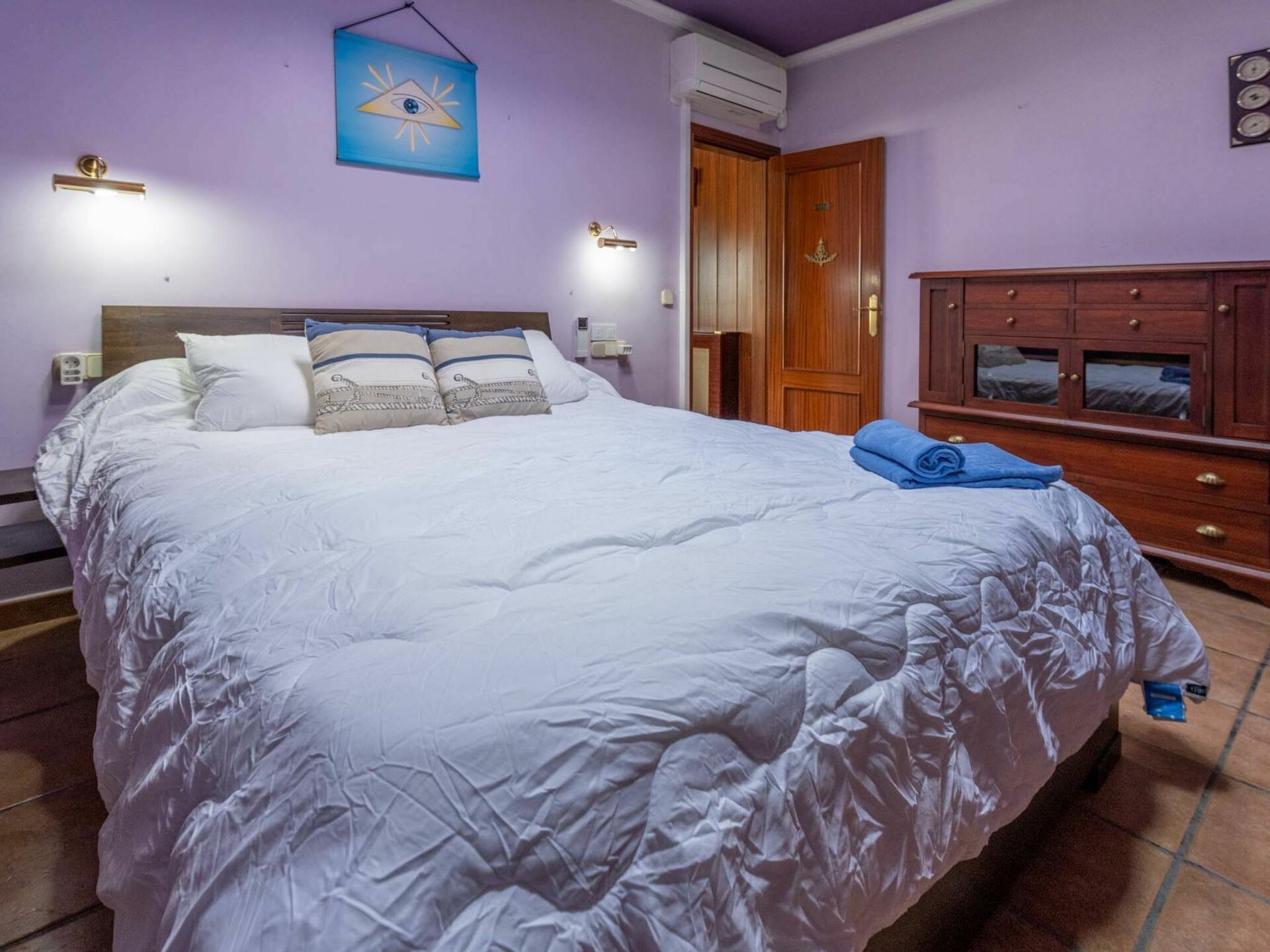 Un dormitorio con una cama grande, un armario de madera y un aire acondicionado de pared.
