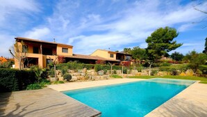 Une maison moderne dotée d’une piscine, entourée d’un jardin bien entretenu et d’une terrasse en bois.