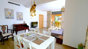 Un coin repas avec une table et des chaises en bois, un téléviseur et un luminaire décoratif suspendu.