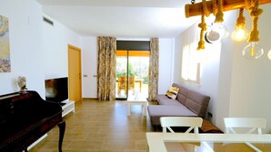 Un salon avec un piano, un canapé, une table basse et un téléviseur.