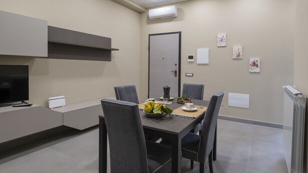 A modern dining area with a table set for four, a television, and a kitchenette. - Lovely apartment for 5 guests with WIFI, A/C, TV and terrace (Meta)