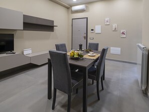 A modern dining area with a table set for four, a television, and a kitchenette. - Nice apartment for 5 people with WIFI, A/C, TV and terrace (Meta)