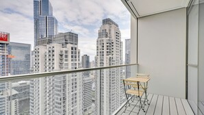 Un balcone con vista su edifici alti, una ringhiera di metallo e un piccolo tavolo di legno.