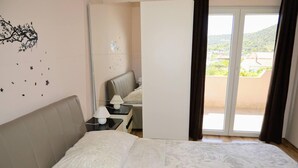 A hotel room with a bed, a nightstand, a lamp, and a view of a balcony with a landscape. - Lovely 2-bed Apartment in Vinisce, Close to Beach (Marina)