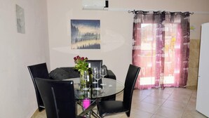 A dining area with a round glass table, black chairs, a vase with flowers, and a painting on the wall. - Lovely 2-bed Apartment in Vinisce, Close to Beach (Marina)