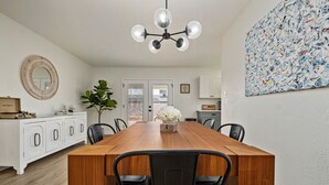 A dining area with a wooden table, black chairs, a chandelier, a white cabinet, and a large abstract painting on the wall. - 10 min to Old Town Scottsdale  (Scottsdale)