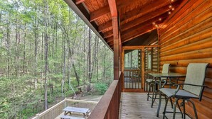 Een houten chalet met terras, zitplaatsen buiten en uitzicht op een bos.