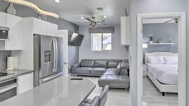 A modern kitchen with a built-in refrigerator, a dining area with a bench, a gray leather sofa, and a white bed in the adjacent room. - Modern Las Vegas Home w/ Patio: 10 Mi to The Strip (Las Vegas)