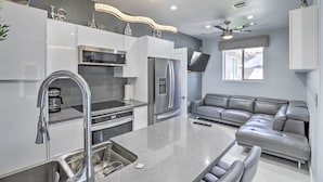 A modern kitchen with stainless steel appliances, a grey countertop, and a grey leather sofa in the living area. - Modern Las Vegas Home w/ Patio: 10 Mi to The Strip (Las Vegas)