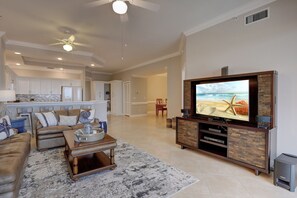 A spacious living room with a large flat-screen TV, a comfortable sofa, and a coffee table.