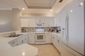 A modern kitchen with white cabinetry, a built-in oven, a microwave, and a refrigerator.