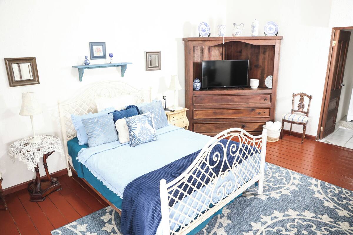 Un dormitorio con cama, televisión, cómoda y silla.