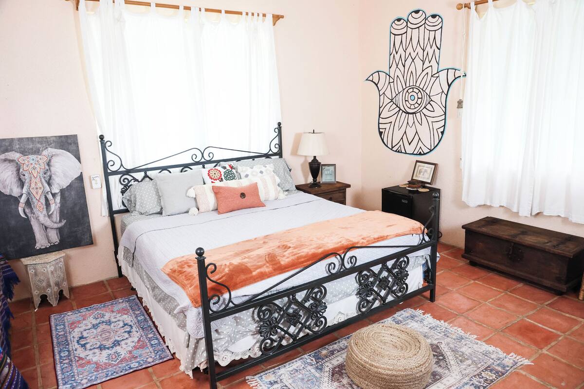 Un dormitorio con cama, mesita de noche, lámpara y decoración mural.