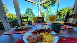 Ein Frühstückstisch mit Toast, Rührei, Speck und zwei Gläsern Orangensaft.