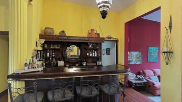 Un espace bar avec un comptoir en bois, des tabourets de bar et un luminaire suspendu.