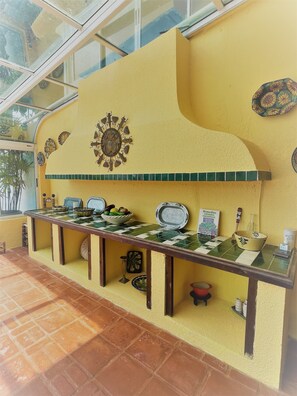A buffet setup with a checkered table, decorative wall art, and a tiled backsplash.