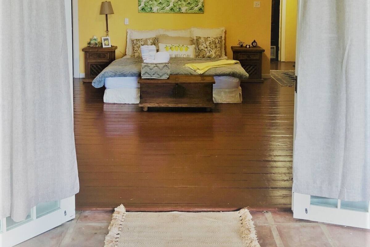 Un dormitorio con cama, mesitas de noche, ventilador de techo y alfombra en el suelo.