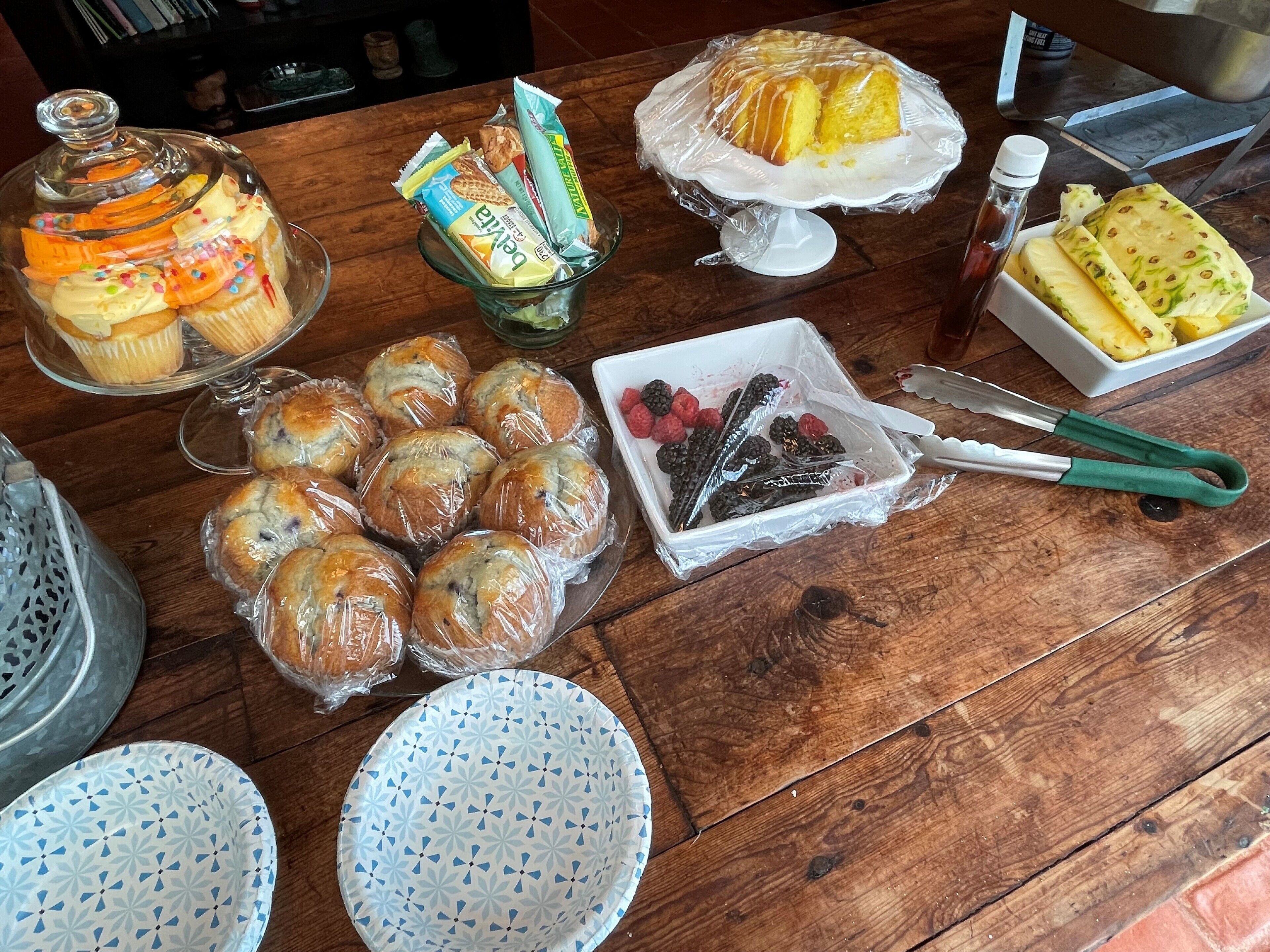 Una mesa de madera con diversos alimentos, como pasteles, un tarro de cristal y un cuenco de bayas.