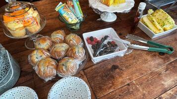 Una mesa de madera con diversos alimentos, como pasteles, un tarro de cristal y un cuenco de bayas.