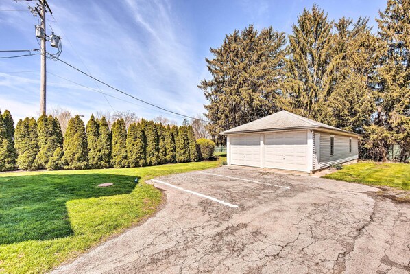 A garage with a white door, a driveway, and a well-maintained lawn. - Home 2 Mi to Hersheypark: Work & Play! (Hershey)