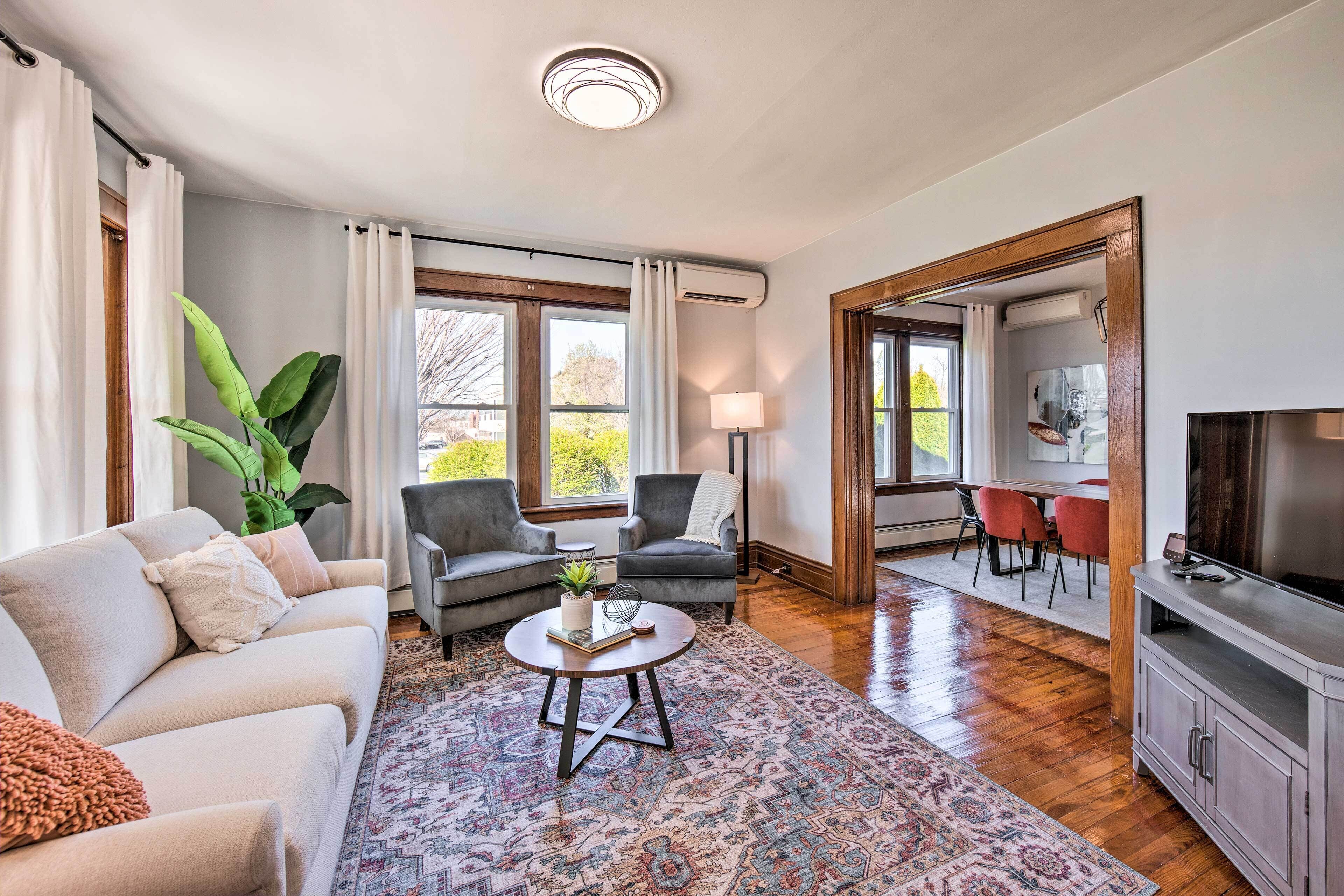 Un salon comprenant un canapé, deux fauteuils, une table basse, un téléviseur et un coin repas avec des chaises et une table.