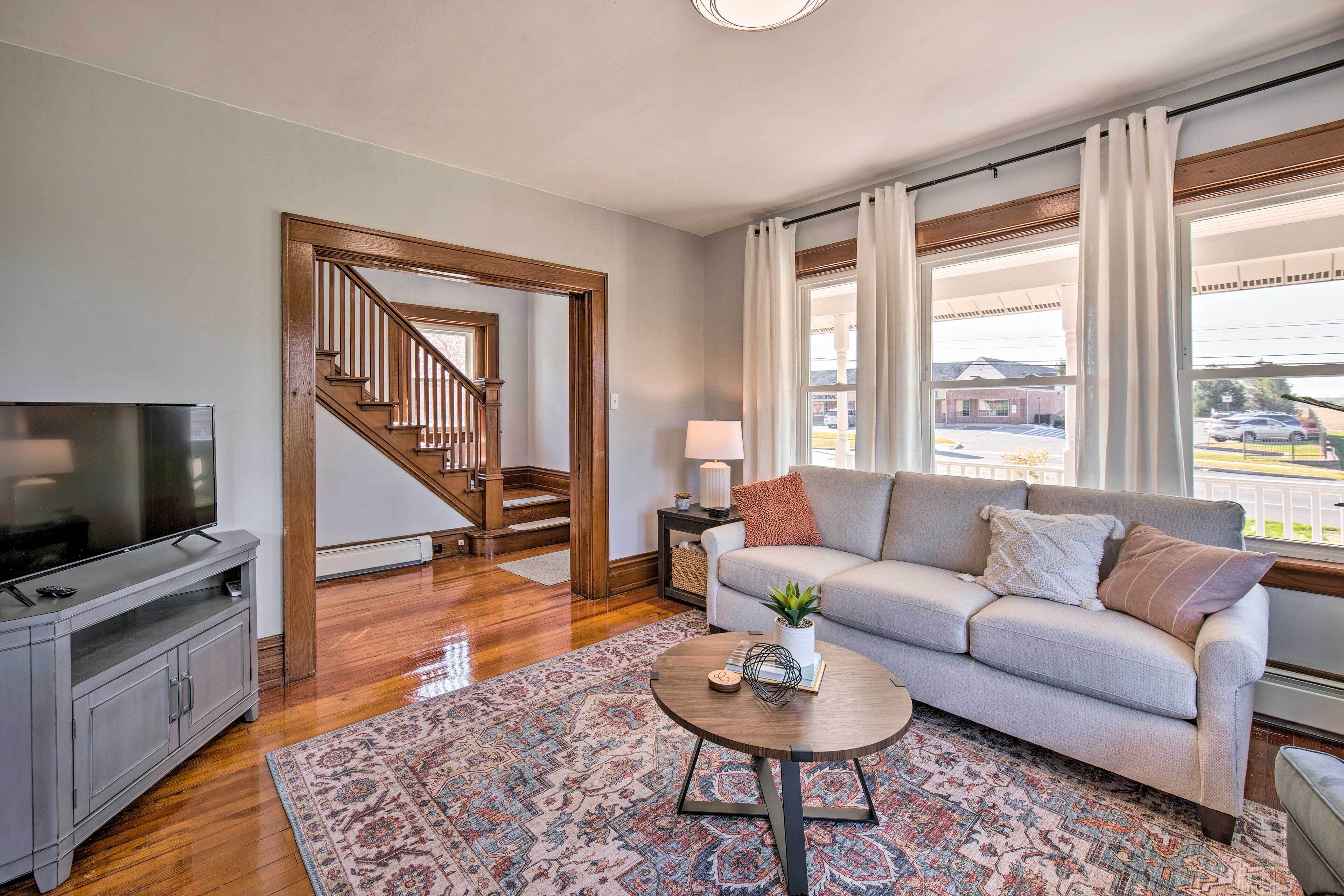 Un salon avec un canapé, une table basse, un téléviseur et un escalier.
