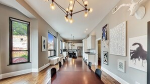 A modern kitchen with white cabinets, a central island, and a dining area with a long wooden table and chairs. - Lovely 4 Bedroom Spot located in Charming Old Town (Chicago)