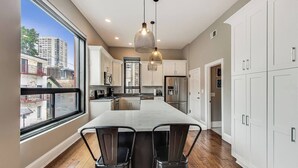 A modern kitchen with a large island, white cabinets, and a view of buildings outside. - Lovely 4 Bedroom Spot located in Charming Old Town (Chicago)