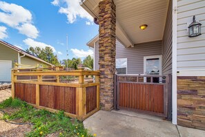 A residential property with a wooden fence, a stone pillar, a gated entrance, and a house with siding and a chimney.