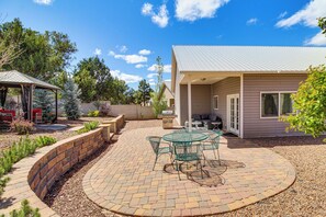 A patio with a circular brick pattern, a glass table with chairs, and a covered seating area.