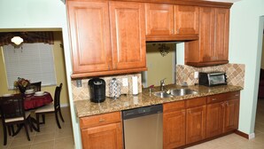Een keuken met houten kastjes, een vaatwasser, een spoelbak en een aanrecht met een koffiezetapparaat en een broodrooster.