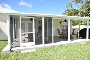 A covered patio with a sliding glass door, a dining table with chairs, and a grill area. - 3BR Home in Boca Raton - Waterfront, Close to Amenities, 20 mins to Beach (Boca Raton)