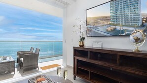 Un balcon agrémenté de meubles en osier, d’une console en bois et d’un tableau encadré représentant un bâtiment.